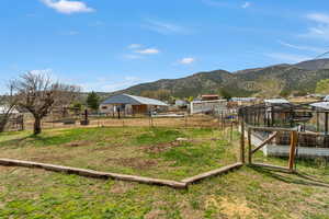 View of yard featuring an outbuilding, a mountain view, and fence