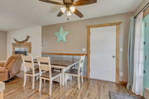 Dining room with a fireplace, a ceiling fan, and wood finished floors