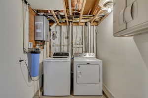 Washroom with washing machine and clothes dryer, cabinet space, and water heater