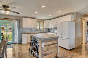 Kitchen featuring recessed lighting, white appliances, white cabinetry, a ceiling fan, and wood finished floors