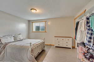 Bedroom featuring a textured ceiling, baseboards, and light floors
