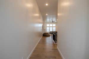 Corridor with an upstairs landing, baseboards, recessed lighting, and wood finished floors