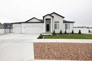View of front facade with board and batten siding, fence, a garage, and concrete driveway