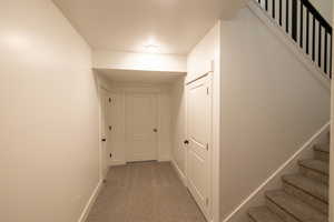 Corridor featuring stairway, carpet flooring, and baseboards