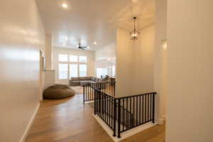 Stairs with wood-type flooring, baseboards, recessed lighting, and ceiling fan with notable chandelier