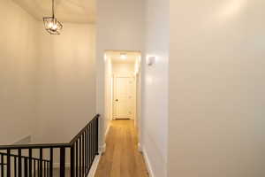 Hallway featuring an upstairs landing, light wood-style floors, and baseboards