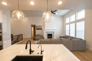 Kitchen featuring light wood-type flooring, a ceiling fan, white cabinets, a sink, and baseboards