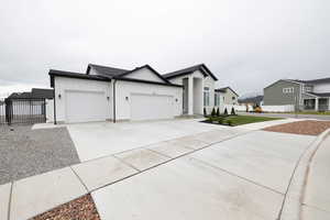 View of front of house featuring concrete driveway, a residential view, board and batten siding, an attached garage, and fence