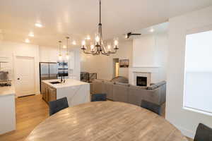 Dining space with light wood-style flooring, a tile fireplace, recessed lighting, and a chandelier