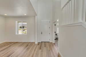 PHOTOS FROM SIMILAR HOME. OPTIONS AND FINISHES WILL VARY. Entrance foyer and formal living room featuring baseboards, light wood finished floors, and recessed lighting