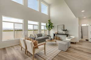 PHOTOS FROM SIMILAR HOME. OPTIONS AND FINISHES WILL VARY. Living room with recessed lighting, light wood finished floors, a high ceiling, and baseboards