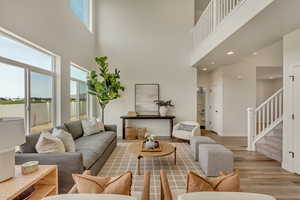 PHOTOS FROM SIMILAR HOME. OPTIONS AND FINISHES WILL VARY. Living area with a high ceiling, wood finished floors, baseboards, and stairway