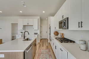 PHOTOS FROM SIMILAR HOME. OPTIONS AND FINISHES WILL VARY. Kitchen featuring a sink, light wood-type flooring, appliances with stainless steel finishes, recessed lighting, and a center island with sink