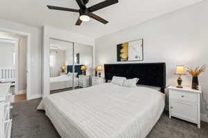 Bedroom with baseboards, dark colored carpet, a closet, and a ceiling fan