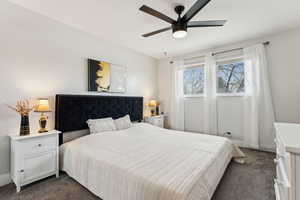 Bedroom featuring ceiling fan, dark colored carpet, and baseboards