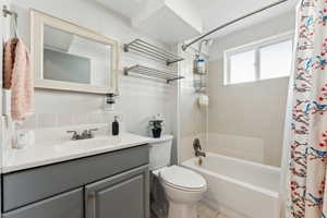Full bath with shower / tub combo with curtain, vanity, and toilet
