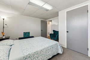 Bedroom featuring carpet flooring, visible vents, and a paneled ceiling
