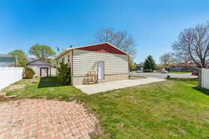 Rear view of house featuring an outdoor structure, fence, a yard, and a shed