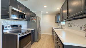 Kitchen featuring light wood-style floors, recessed lighting, appliances with stainless steel finishes, light countertops, and baseboards
