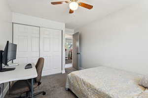 Bedroom with dark carpet, a closet, and ceiling fan