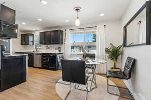 Kitchen with stainless steel dishwasher, dark cabinets, light countertops, electric stove, and light wood finished floors