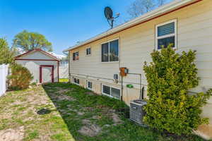 Back of property with a shed, central air condition unit, fence, and an outbuilding