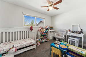 Carpeted bedroom featuring a ceiling fan