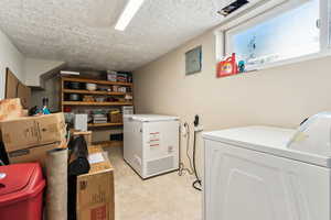 Laundry area with washer and dryer, laundry area, light tile patterned floors, and a textured ceiling