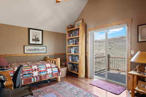 Bedroom with access to outside, hardwood / wood floors, and vaulted ceiling