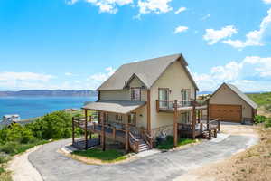 View of front facade with stone siding, stucco siding, a balcony, roof with shingles, and driveway