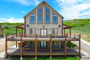 Rear view of house with a deck, french doors, stucco siding, and stone siding