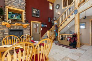Dining space featuring a stone fireplace, stairway, high vaulted ceiling, and tile  finish floor
