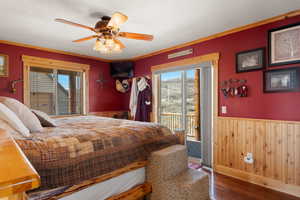 Bedroom with access to outside, multiple windows, a wainscoted wall, and wood  floors