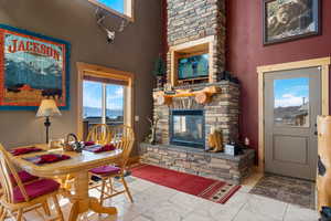 Great room featuring a stone fireplace, a high ceiling, and a healthy amount of sunlight