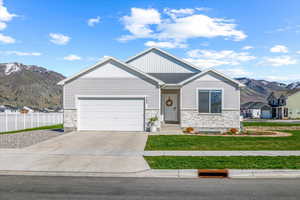 View of front of property with a mountain view, fence, stone siding, and concrete driveway