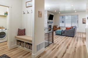 Mudroom with washer / clothes dryer, wood finished floors, a fireplace, and visible vents
