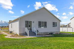 Back of house featuring a mountain view, fence, central AC unit, and a lawn
