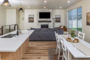 Kitchen with hanging light fixtures, a sink, light wood-style floors, a fireplace, and recessed lighting