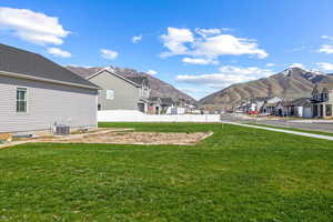 View of yard with a mountain view, fence, a residential view, and central air condition unit