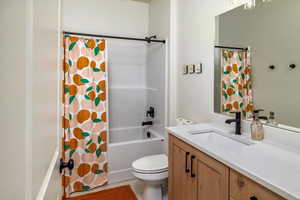 Bathroom featuring shower / bath combo with shower curtain, vanity, and toilet