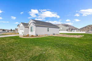 View of side of home with central air condition unit, a yard, fence, an attached garage, and driveway