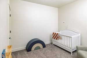 Carpeted bedroom with a nursery area and baseboards