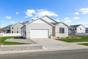 Ranch-style house with an attached garage, driveway, stone siding, and fence