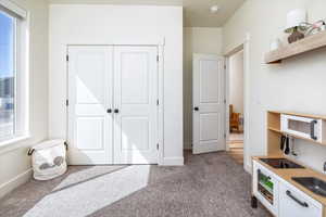 Bedroom featuring a closet, baseboards, multiple windows, and dark colored carpet