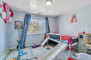 Carpeted bedroom with visible vents, baseboards, and a textured ceiling