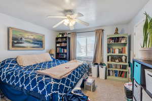 Carpeted bedroom featuring a ceiling fan