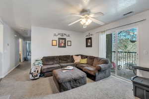 Living area with ceiling fan, a textured ceiling, visible vents, carpet flooring, and baseboards