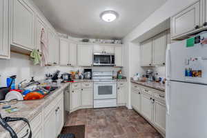 Kitchen featuring a sink, light countertops, appliances with stainless steel finishes, and stone finish floor