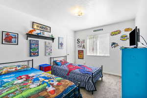 Carpeted bedroom with a textured ceiling and baseboards