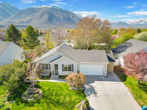 View of front facade with an attached garage, driveway, a front yard, and a mountain view